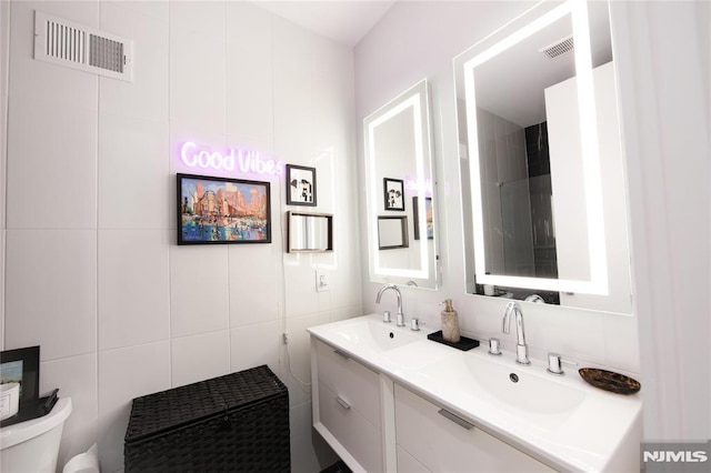 bathroom with toilet, vanity, and tile walls