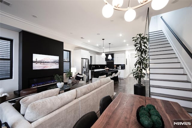 living room featuring concrete floors, ornamental molding, and a notable chandelier