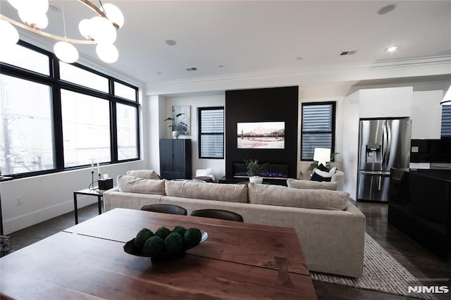 living room with crown molding, dark wood-type flooring, and an inviting chandelier