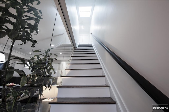 stairway with a skylight and ornamental molding