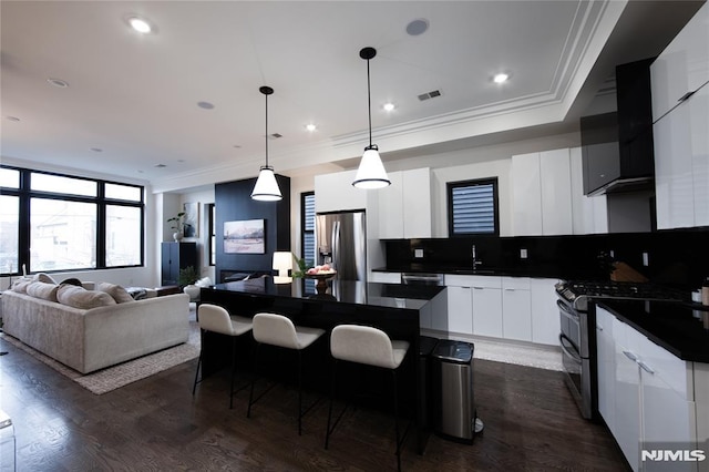 kitchen with stainless steel appliances, white cabinets, tasteful backsplash, and a center island