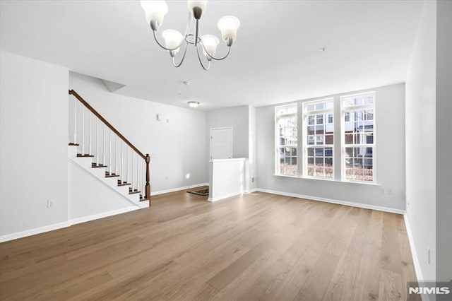 unfurnished living room with light wood-type flooring and a chandelier