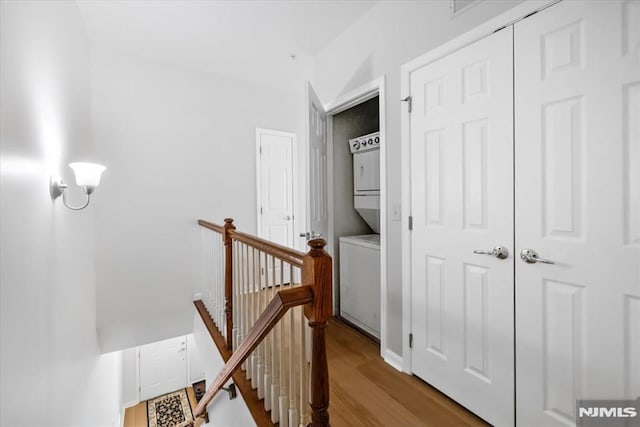 corridor featuring stacked washer and dryer and wood-type flooring