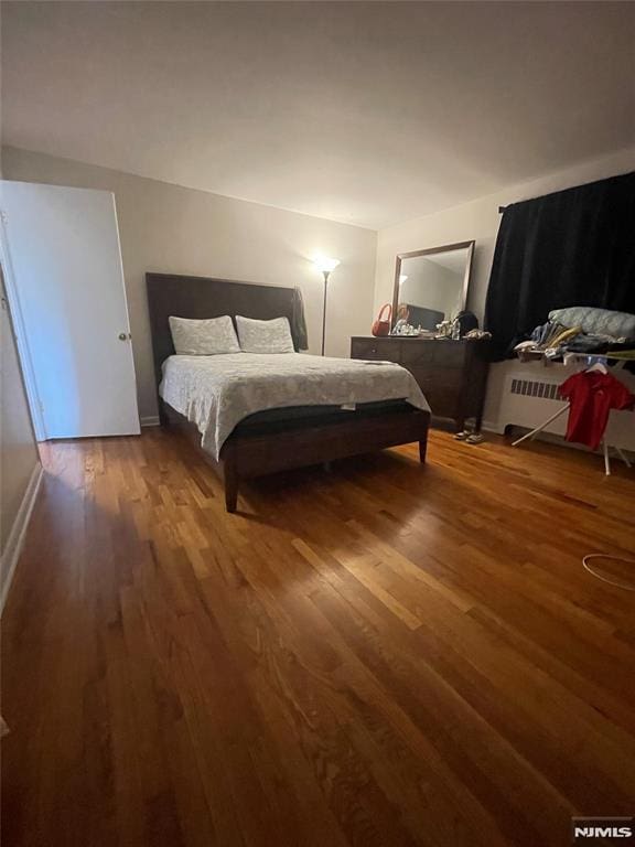 bedroom with radiator heating unit and hardwood / wood-style flooring