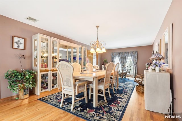 dining space featuring hardwood / wood-style flooring and an inviting chandelier