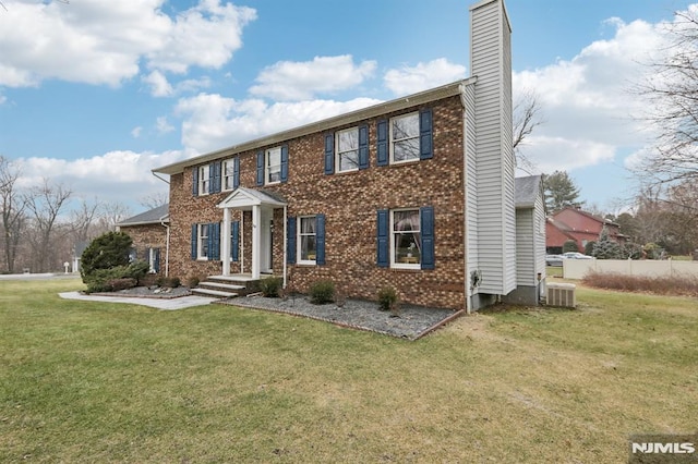 colonial inspired home featuring cooling unit and a front lawn