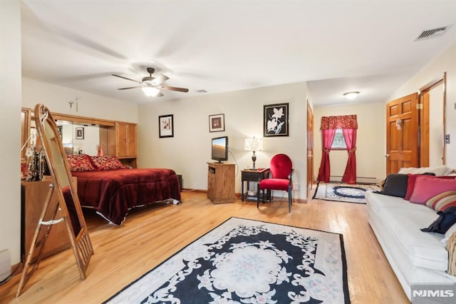 bedroom with ceiling fan, baseboard heating, and light hardwood / wood-style floors