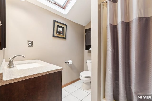 bathroom featuring toilet, vanity, lofted ceiling with skylight, and tile patterned floors