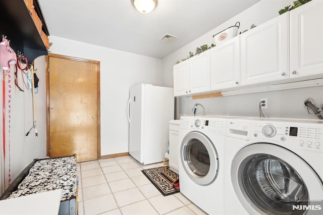 washroom with washing machine and clothes dryer, light tile patterned floors, and cabinets