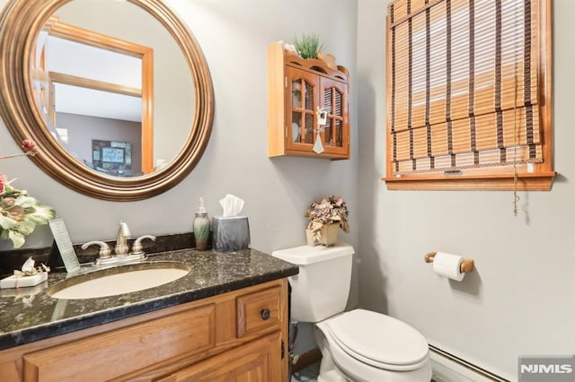 bathroom with toilet, vanity, and a baseboard heating unit