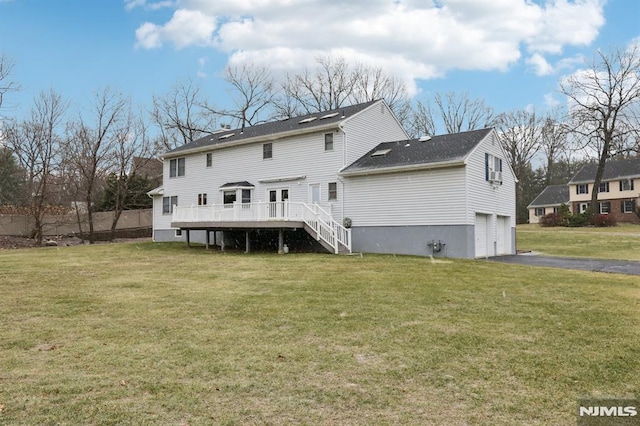 rear view of house featuring a yard, a garage, and a wooden deck