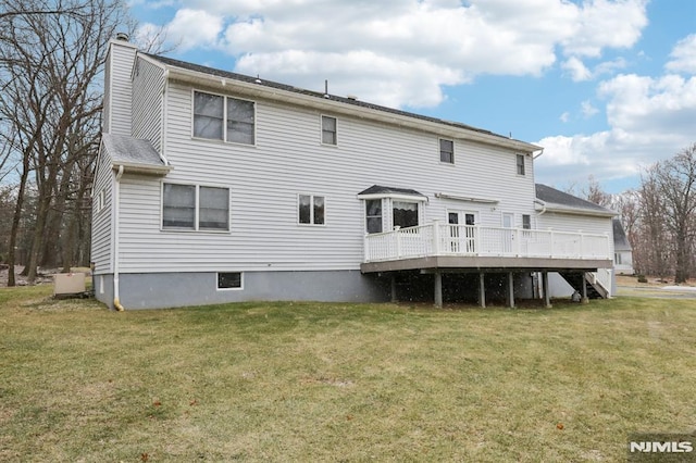 rear view of property featuring a deck and a lawn