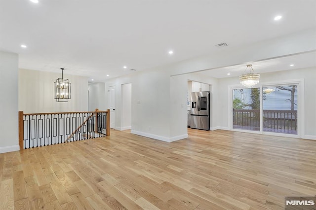 unfurnished living room featuring light wood-type flooring and a chandelier