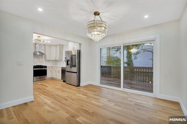 kitchen featuring stainless steel appliances, a notable chandelier, decorative backsplash, and white cabinetry