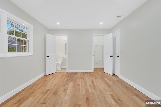 unfurnished bedroom featuring light wood-type flooring, a closet, and connected bathroom