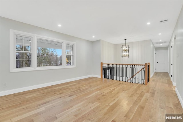 unfurnished room with light hardwood / wood-style floors and a notable chandelier