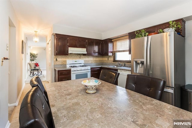 kitchen with sink, white appliances, tasteful backsplash, and dark brown cabinetry