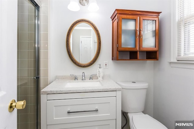 bathroom with toilet, walk in shower, and vanity