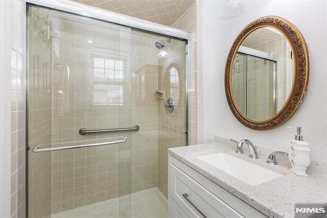 bathroom featuring a shower with door and vanity