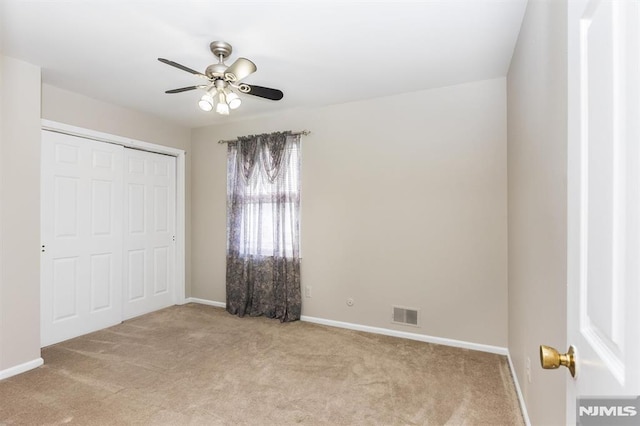 unfurnished bedroom with ceiling fan, a closet, and light carpet