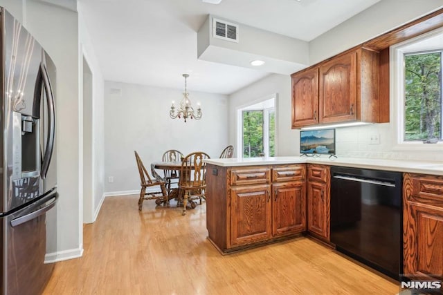 kitchen with dishwasher, a notable chandelier, stainless steel refrigerator with ice dispenser, light hardwood / wood-style flooring, and backsplash