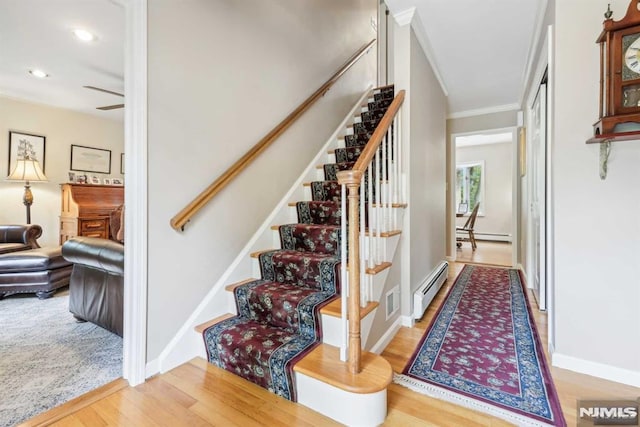 stairs featuring a baseboard heating unit, crown molding, and hardwood / wood-style floors