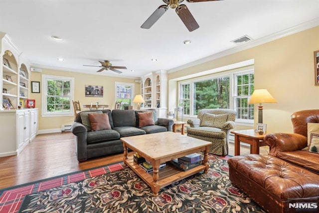 living room with built in shelves, ceiling fan, crown molding, and wood-type flooring