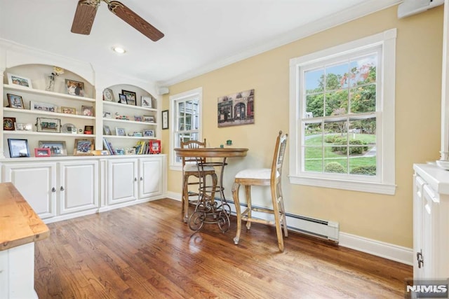 interior space featuring ceiling fan, hardwood / wood-style floors, ornamental molding, a baseboard heating unit, and built in shelves