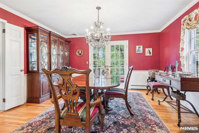 dining area with french doors, a chandelier, ornamental molding, and light hardwood / wood-style floors