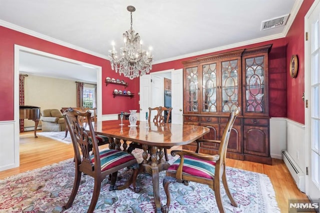 dining area with baseboard heating, light hardwood / wood-style floors, crown molding, and a chandelier