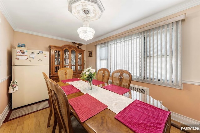 dining area with wood-type flooring, ornamental molding, a wealth of natural light, and a chandelier