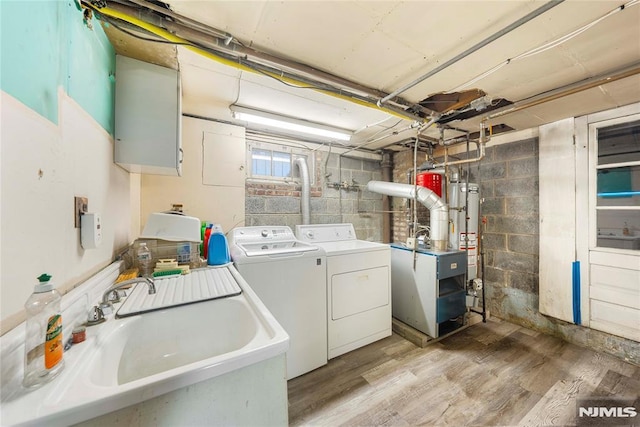 laundry room with washer and dryer, gas water heater, light hardwood / wood-style flooring, and sink