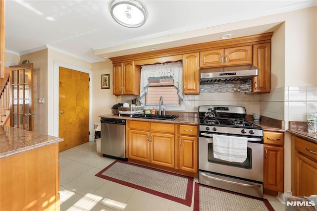 kitchen with stainless steel appliances, dark stone countertops, sink, light tile patterned flooring, and crown molding