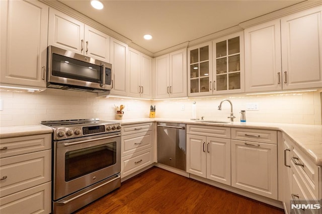 kitchen with backsplash, sink, white cabinetry, appliances with stainless steel finishes, and dark hardwood / wood-style flooring