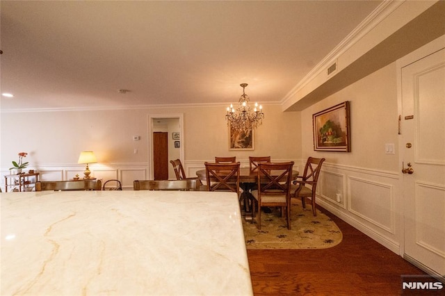 dining space with dark wood-type flooring, crown molding, and an inviting chandelier