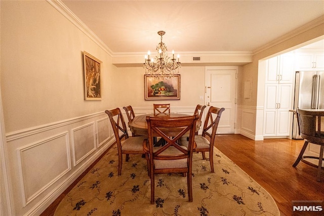 dining room featuring an inviting chandelier, ornamental molding, and hardwood / wood-style floors