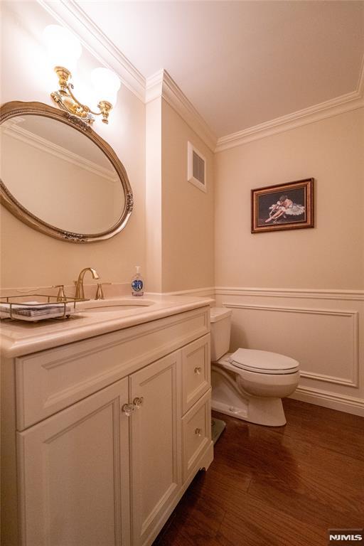 bathroom with hardwood / wood-style flooring, toilet, vanity, and crown molding