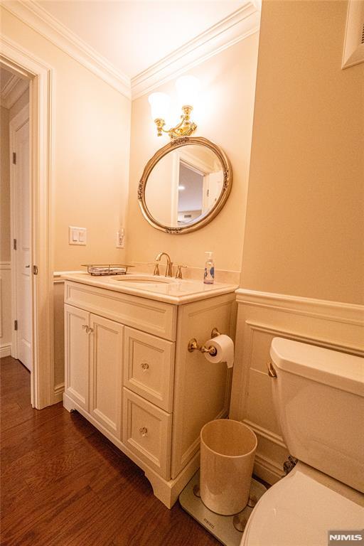 bathroom featuring toilet, ornamental molding, wood-type flooring, and vanity