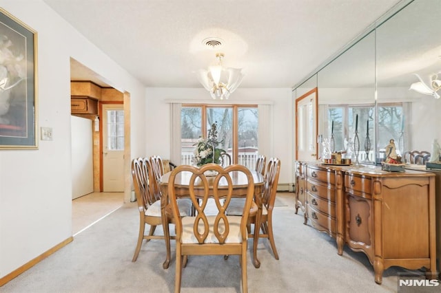 carpeted dining space with a baseboard heating unit and an inviting chandelier