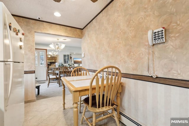 dining space with ornamental molding, baseboard heating, an inviting chandelier, and a textured ceiling