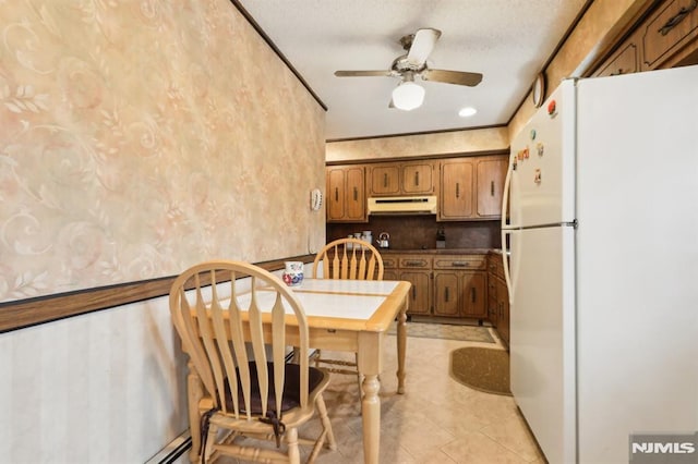 kitchen with a textured ceiling, decorative backsplash, ceiling fan, white refrigerator, and ornamental molding