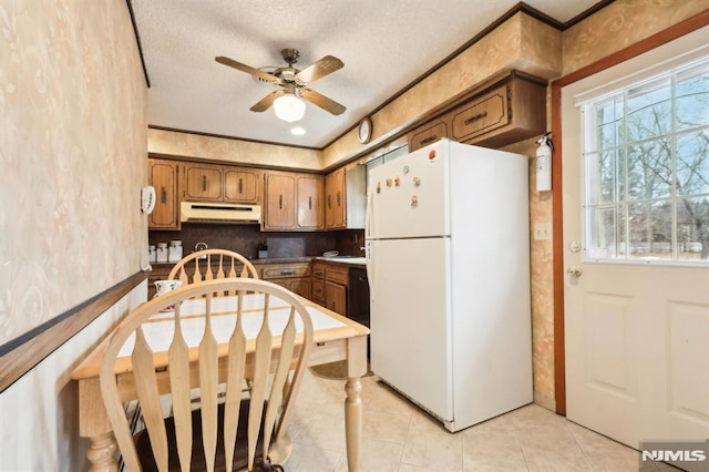 kitchen with white refrigerator, a textured ceiling, ceiling fan, light tile patterned floors, and decorative backsplash