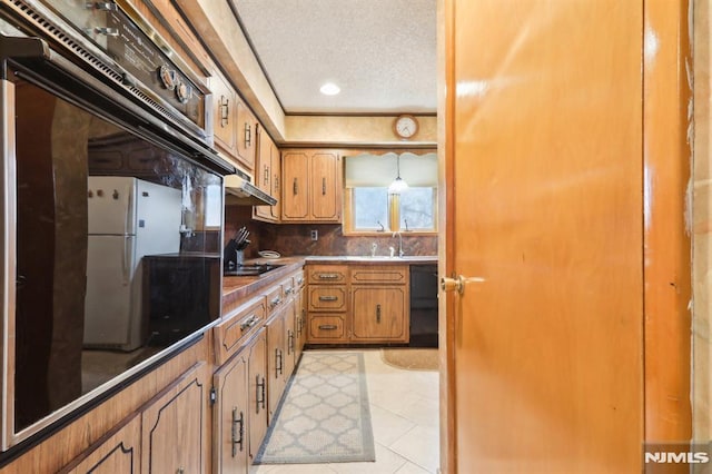 kitchen with a textured ceiling, light tile patterned floors, black appliances, decorative backsplash, and sink