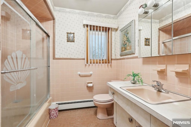 full bathroom featuring tile patterned flooring, tile walls, combined bath / shower with glass door, vanity, and baseboard heating