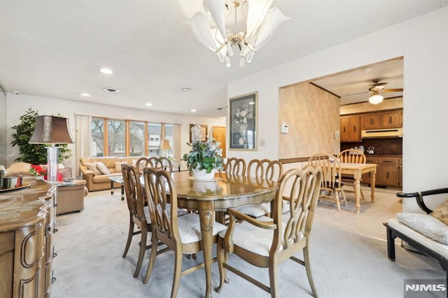 carpeted dining room featuring ceiling fan with notable chandelier