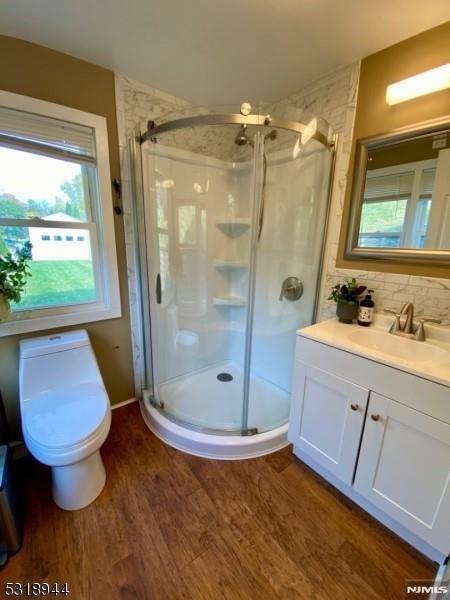 bathroom featuring toilet, walk in shower, vanity, hardwood / wood-style flooring, and backsplash