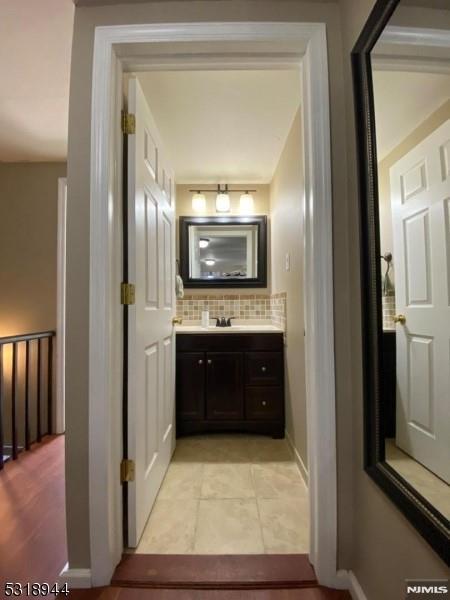 bathroom with tile patterned flooring, tasteful backsplash, and vanity