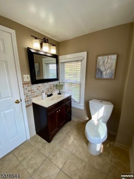 bathroom featuring vanity, decorative backsplash, and toilet