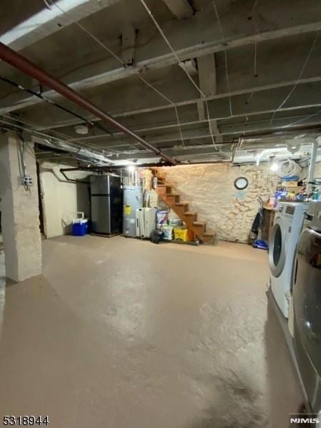 basement featuring stainless steel fridge, electric water heater, and washing machine and clothes dryer