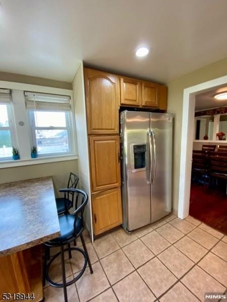 kitchen featuring light tile patterned floors and stainless steel refrigerator with ice dispenser